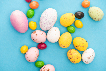 Top view of bright colorful sweets and easter eggs on blue background