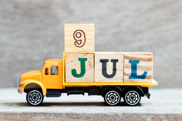 Wall Mural - Truck hold letter block in word 9jul on wood background (Concept for date 9 month July)