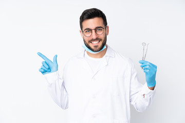 Wall Mural - Dentist man holding tools isolated on white background pointing finger to the side