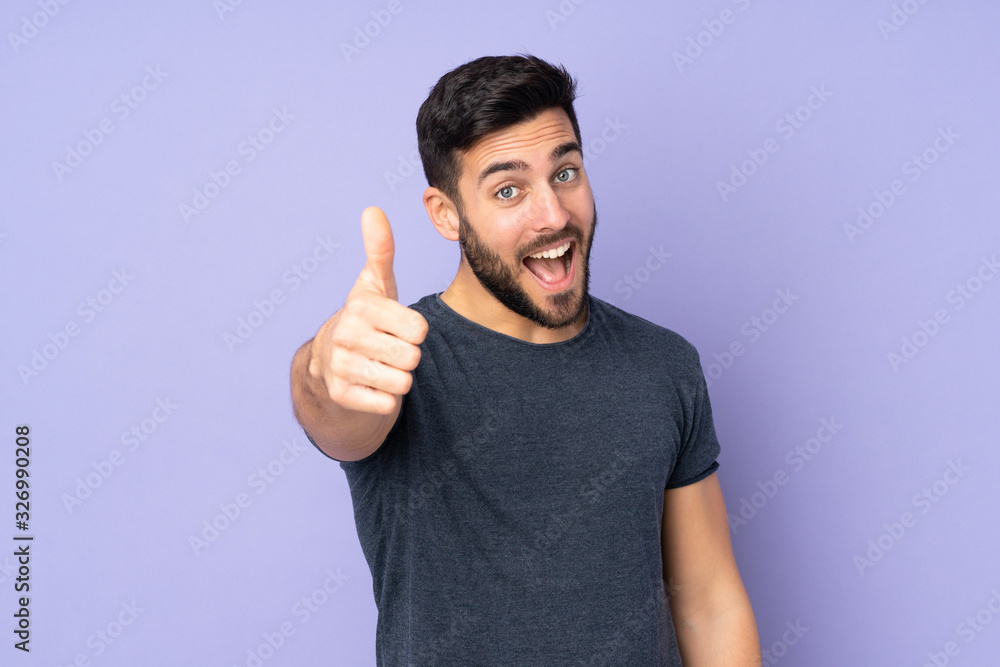 Caucasian handsome man with thumbs up because something good has happened over isolated purple background - obrazy, fototapety, plakaty 