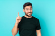 © luismolinero - Caucasian handsome man isolated on blue background pointing with the index finger a great idea