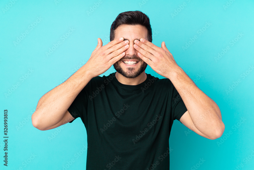 Caucasian handsome man isolated on blue background covering eyes by ...