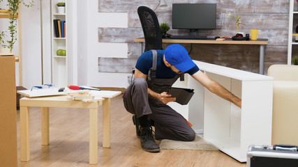 Male worker using modern technology for furniture assembly