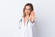 © luismolinero - Young woman over isolated white background wearing a doctor gown and making stop sign