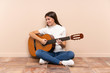 © luismolinero - Young woman with guitar sitting on the floor laughing