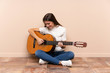 © luismolinero - Young woman with guitar sitting on the floor