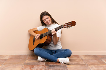 Young woman with guitar sitting on the floor