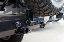 Close-up On A New Black Tow Hitch Installed On A Offroad Car With An Iron Black Bumper In A Vehicle Repair Shop. The Device For The Transport Of The Trailer In The Workshop.