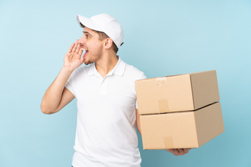 Wall Mural - Delivery caucasian man isolated on blue background shouting with mouth wide open