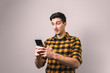 © Andrei - young man looking into his phone amazed by unbelievable news or social media post