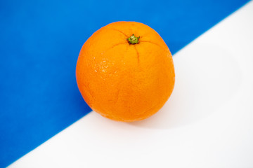 one whole orange lies on a white-blue background