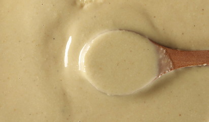 Sesame butter, paste tahini in wooden spoon background and texture