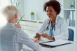 © lordn - A female doctor sits at her office and examining elderly female patient