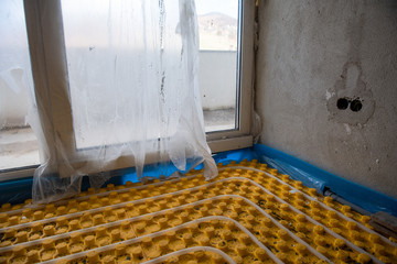 yellow underfloor heating installation with white pipes