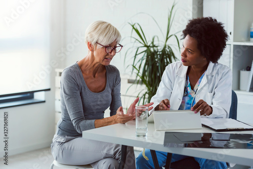 Cuadros en Lienzo A female doctor sits at her desk and chats to an elderly female patient while lo