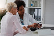 © lordn - A female doctor sits at her desk and chats to an elderly female patient while looking at her  test results