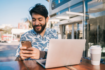 Wall Mural - Young man using his laptop and mobile phone.