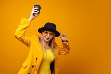 Wall Mural - Stylish trendy young woman in bright clothes on a yellow background. Cool blonde