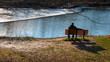 © HRTNT Media - A Lone Man Sitting on a Bench in a Forest Admiring a Waterfall from a Dam and a lake