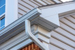 Close up of white frame gutter guard system,decorative trim,  eaves through, fascia, drip edge, colonial white soffit with ventilation, luxury American single family home neighborhood USA