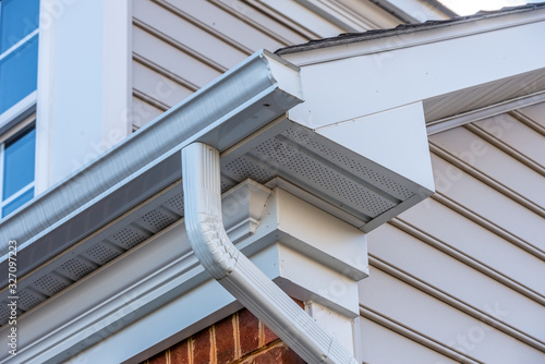 Close up of white frame gutter guard system,decorative trim,  eaves through, fascia, drip edge, colonial white soffit with ventilation, luxury American single family home neighborhood USA