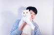 © Steve - An Asian man holding a pure white British short pet cat