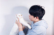 © Steve - An Asian man holding a pure white British short pet cat who wants to break free