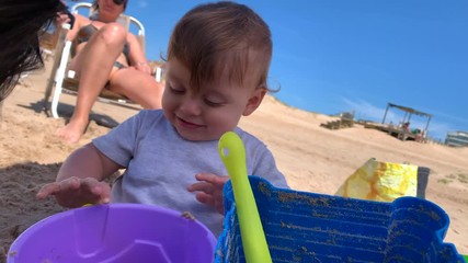 Wall Mural - Baby playing at beach, toddler infant plays with buckets and shovel