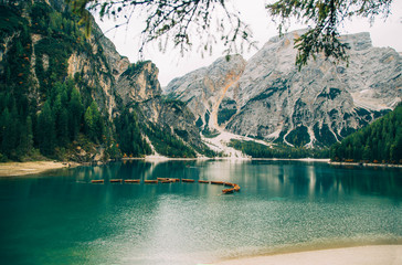 Free space for an inscription of text poster on backdrop of alpine Lake Braies boats turquoise water white road leading top majestic mountains green forest fantastic nature no people. Photo wallpaper