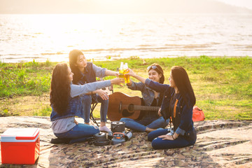 Blurry image of Happy teenagers picnic by the lake amid soft sunright. A group of friends who drink happily. Relaxation concept.