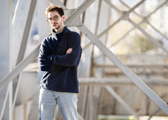 Wall Mural - fashion guy stands posing near a black brick wall in sunglasses