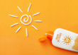 © adragan - Sunscreen on orange background. Plastic bottle of sun protection and white sun-shaped cream