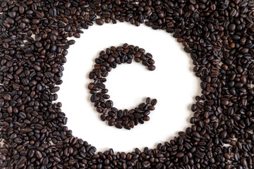 Letter C made out of aromatic coffee beans, top view, isolated on white background. Letter from word Coffee.