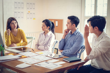 Wall Mural - group of young asian designer in smart casual wear talking and development ux app on mobile phone du