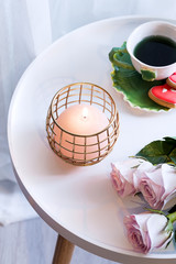 Canvas Print - Romantic greeting card with roses flowers, aromatic burning candle and cup of tea on a white round table.