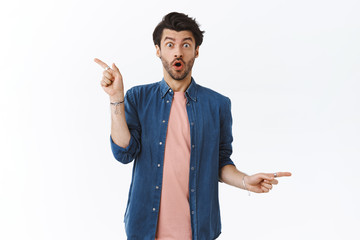Wall Mural - Amused, fascinated bearded hipster guy in modern outfit, gasping from amazement and surprised, pointing different sides, showing left right choices, excited so much good variants of gifts