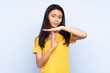 Teenager Chinese woman isolated on blue background making time out gesture