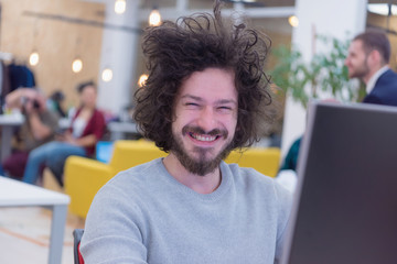 Young male web developer smiling at work while the Group of a young business multiethnic people brainstorming and discussing business plan on meeting at sunny bright office interior.