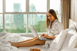 girl in bed with a laptop by the window on the background of skyscrapers