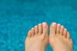 beautiful legs with french pedicure on the background of the pool