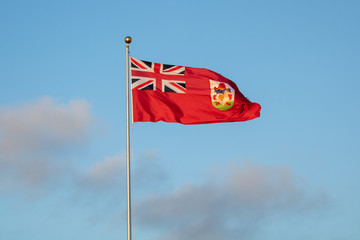 Vibrant Bermuda flag flying high with a blue sky behind it. 