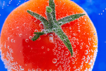 Fresh red Tomatoes in splash of water. juicy vegetables close-up, macro selective focus.