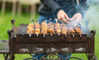 man cooks barbecue, in the process of cooking rotates a skewer with meat, close-up
