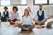 © luckybusiness - Businesswoman meditating at work.group of business coworkers meditating together.