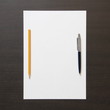 © Stanislav - Template of white paper with pen and pencil on dark wenge color wooden background.