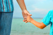 © Kostia - hands of happy parent and child at sea greece background