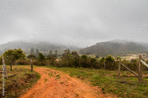 Bucolic landscape with road in winter day, cloudy and with drizzle Poster Mural XXL
