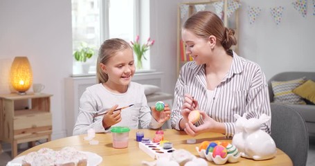 Sticker - Happy mother and daughter painting eggs for Easter celebration at home