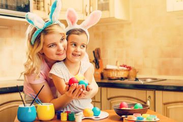 Wall Mural - daughter and mother in rabbit costume prepare for Easter and paint eggs