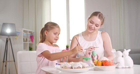 Sticker - Happy mother and daughter painting eggs for Easter celebration at home